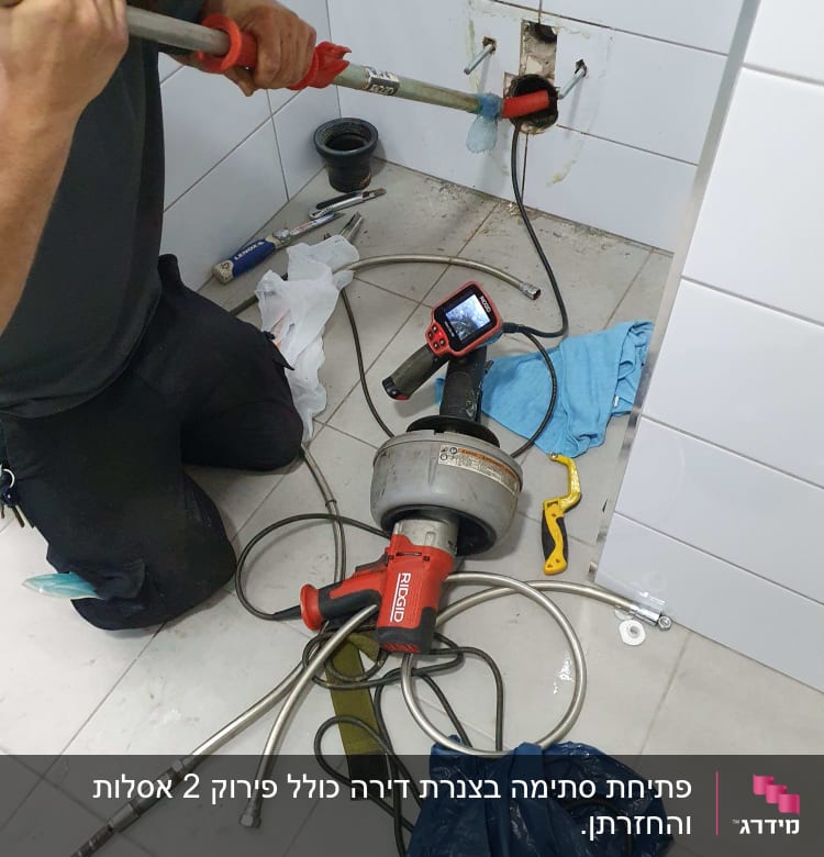 אינסטלטור עובד עם כלי עבודה על צינור קיר
